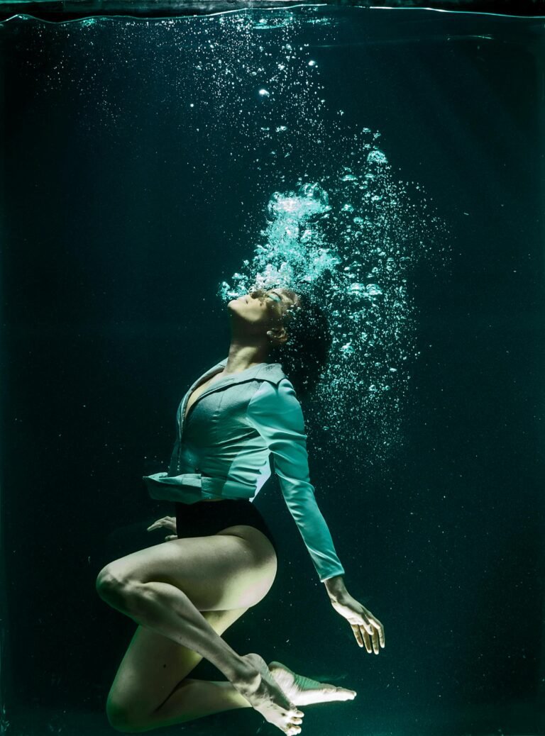 Dramatic photo of a woman diving underwater in stylish attire.